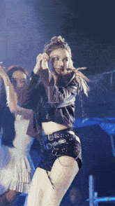 a woman in a crop top and shorts is dancing in front of a sign that says lilyrose38 on it