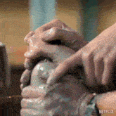 a close up of a person 's hands making a pottery bowl .