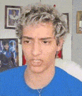 a young man with blonde hair and a blue shirt is making a face