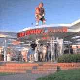 a statue of a hockey player is standing on top of a building that says san mikito 's donuts