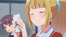 a girl with blonde hair is looking at a cell phone with her eyes closed