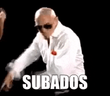 a man in a white shirt and sunglasses is dancing with the words subados written on the screen .