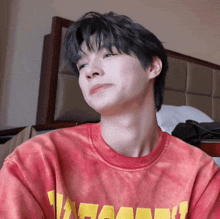 a young man wearing a red tie dye t-shirt with a yellow lettering on it