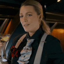 a woman wearing a black shirt and suspenders is holding a martini glass