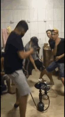 a group of young men are dancing around a hookah in a room .