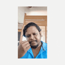 a man in a blue shirt is making a funny face with the word haat written on the wall behind him