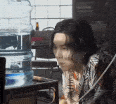 a person sitting in front of a water cooler with a bottle of beer in the background