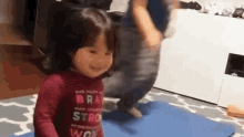 a little girl is standing on a blue yoga mat .