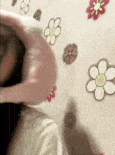 a child laying on a bed with flowers on the wall