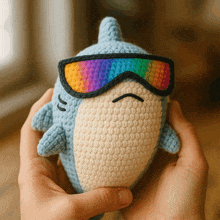 a person is holding a crocheted shark with sunglasses on