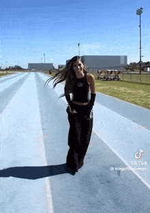 a woman is dancing on a track and has a tiktok account