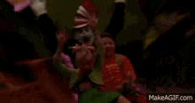 a cat in the hat is holding a baby in his arms while a group of children are riding a roller coaster .