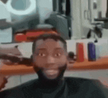 a man is getting his hair cut at a barber shop and smiling .