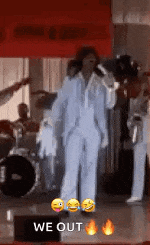 a man in a suit is singing into a microphone on a stage with a band behind him .