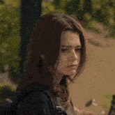 a girl with brown hair and a black backpack looks to the side