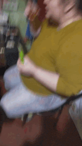 a woman in a yellow shirt is sitting on a chair holding a green object