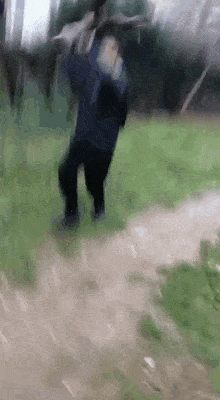 a person is standing on a dirt path in a field holding a sword .