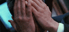 a man covering his face with his hands in a suit