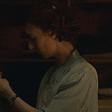 a woman with red hair is wearing a light blue shirt