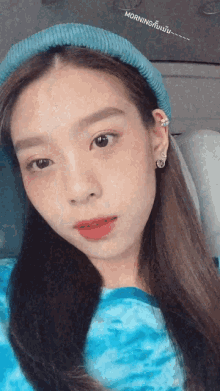 a woman wearing a blue headband and a blue shirt has morning written on the bottom of her face