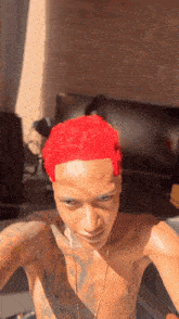 a shirtless man with red hair takes a selfie in front of a brick wall