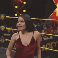 a woman in a red dress is standing in a wrestling ring with her eyes closed .