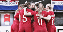 a group of female soccer players hugging each other in front of a sign that says an de donk