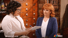 two women are standing next to each other with a nbc logo in the background