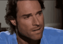 a man in a blue shirt is making a funny face