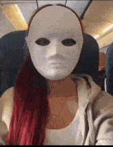 a woman with red hair is wearing a white mask while sitting on an airplane .