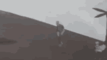 a blurry picture of a person standing on top of a hill with a windmill in the background .