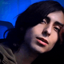 a close up of a young man 's face with a blue background