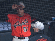 a baseball player wearing a red jersey that says giants on it