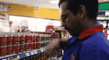 a man in a blue uniform reaches for a can of cafalfa