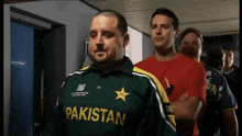 a man in a green pakistan shirt stands in a line