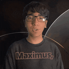 a young man wearing glasses and a black shirt that says maximus