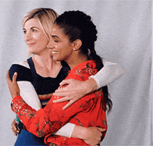 two women are hugging each other while standing next to each other .