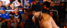 a man in a hat is standing in front of a crowd of people in a stadium .