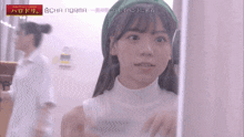 a girl wearing a green hat and a white turtleneck is standing in front of a sign that says icha norma