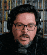 a man with glasses and a beard wears headphones