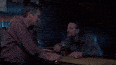 two men are sitting at a bar and one of them is saying some kind of distressed goddess