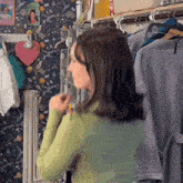 a woman in a green shirt is standing in front of a closet full of clothes