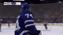 a hockey player with the number 74 on his jersey stands on the ice