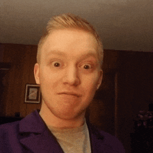 a man wearing a purple jacket is making a face