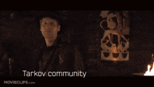 a man in a hat is standing in a dark room with the words tarkov community written below him