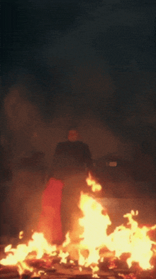 a man is standing in front of a large fire