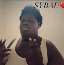a man in a white tank top stands in front of a sign that says sybaum
