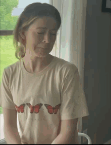 a woman wearing a white t-shirt with butterflies on it