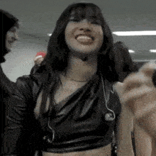 a woman in a black leather top is smiling while standing in a room with other people .
