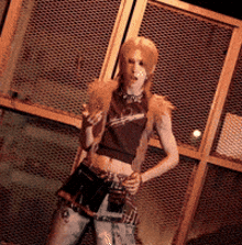a woman in a crop top and shorts stands in front of a fence